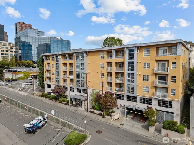 a front view of a building with glass windows and plants