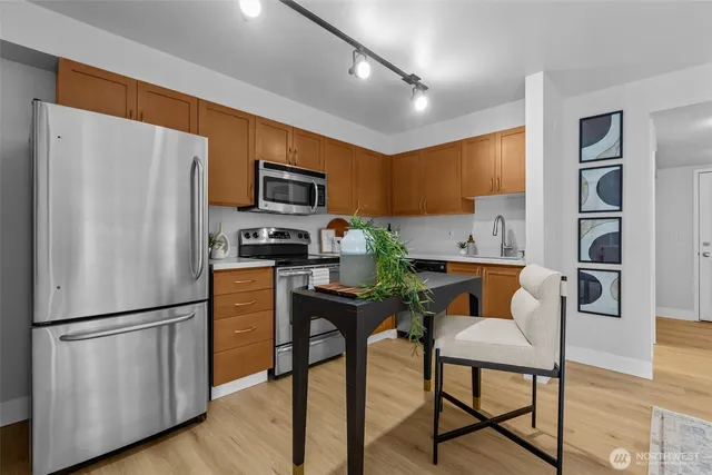 a kitchen with stainless steel appliances a refrigerator a stove a microwave a dining table and chairs with wooden floor