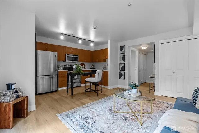 a kitchen with stainless steel appliances kitchen island granite countertop a refrigerator a stove a sink a dining table and chairs with wooden floor