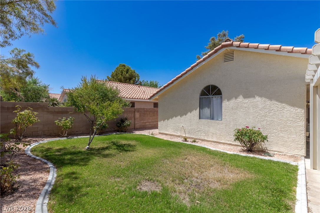2803 Mirage Road Henderson, NV 89074 - Photo 35 of 39 A curved green lawn is bordered by low-maintenance gravel beds and a stucco privacy wall.