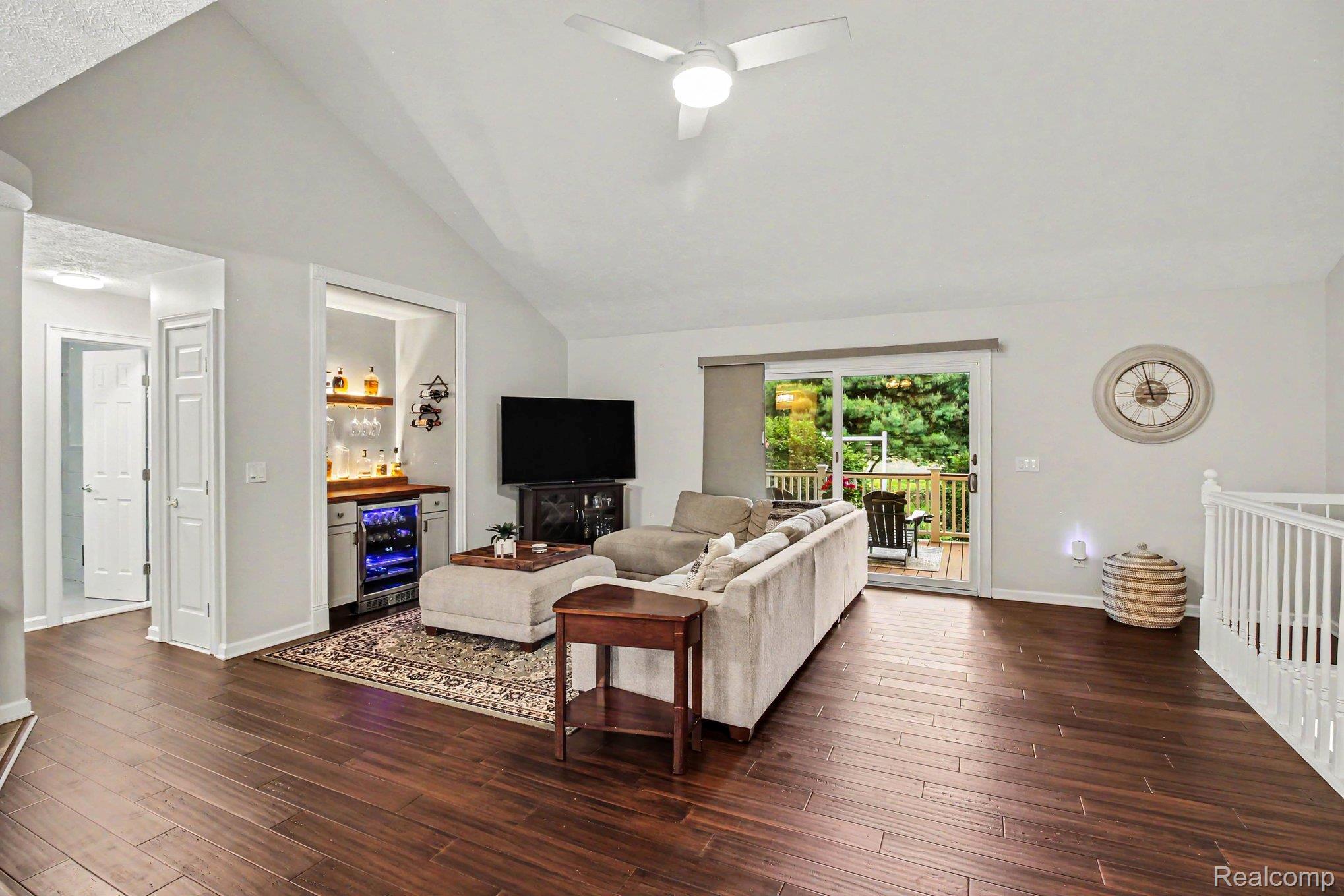 5183 North Owosso Road Fowlerville, MI 48836 - Photo 6 of 27 Living room with vaulted ceiling, a bar, ceiling fan, dark wood finished floors, and beverage cooler