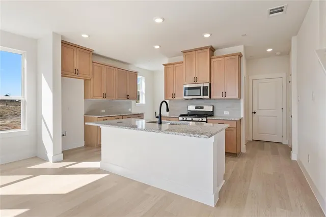 a kitchen with stainless steel appliances granite countertop a refrigerator sink and white cabinets