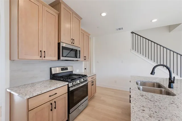 a kitchen with granite countertop a stove a sink and a microwave