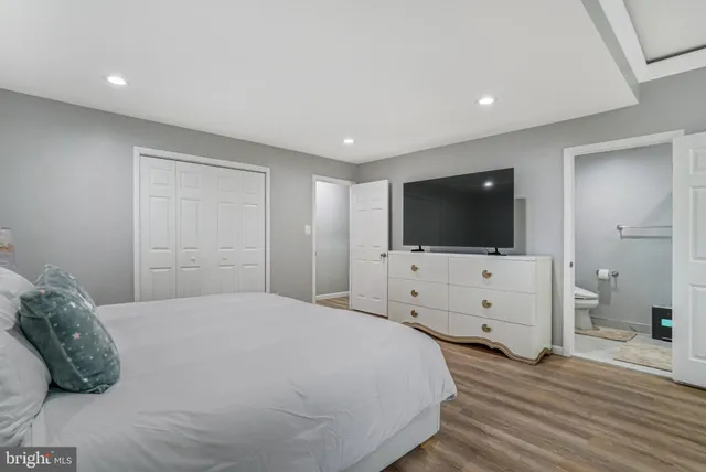 a bedroom with a flat screen tv on dresser and a flat screen tv
