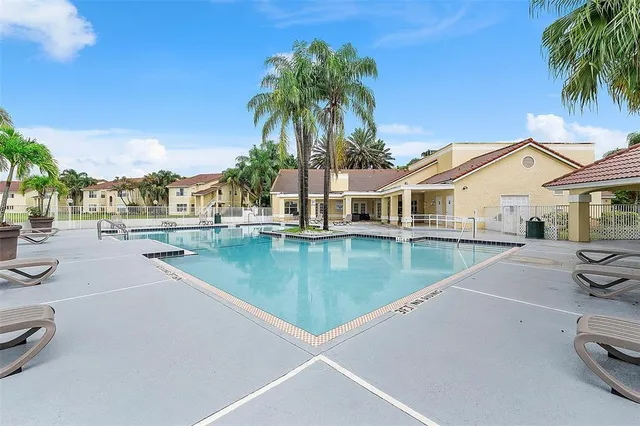 a view of a swimming pool with a lawn chairs under palm trees