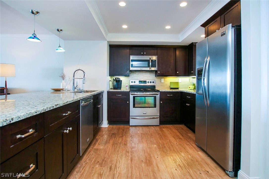 15011 Punta Rassa Road, Unit 204 Fort Myers, FL 33908 - Photo 9 of 23 a kitchen with stainless steel appliances granite countertop a refrigerator a sink dishwasher and wooden cabinets