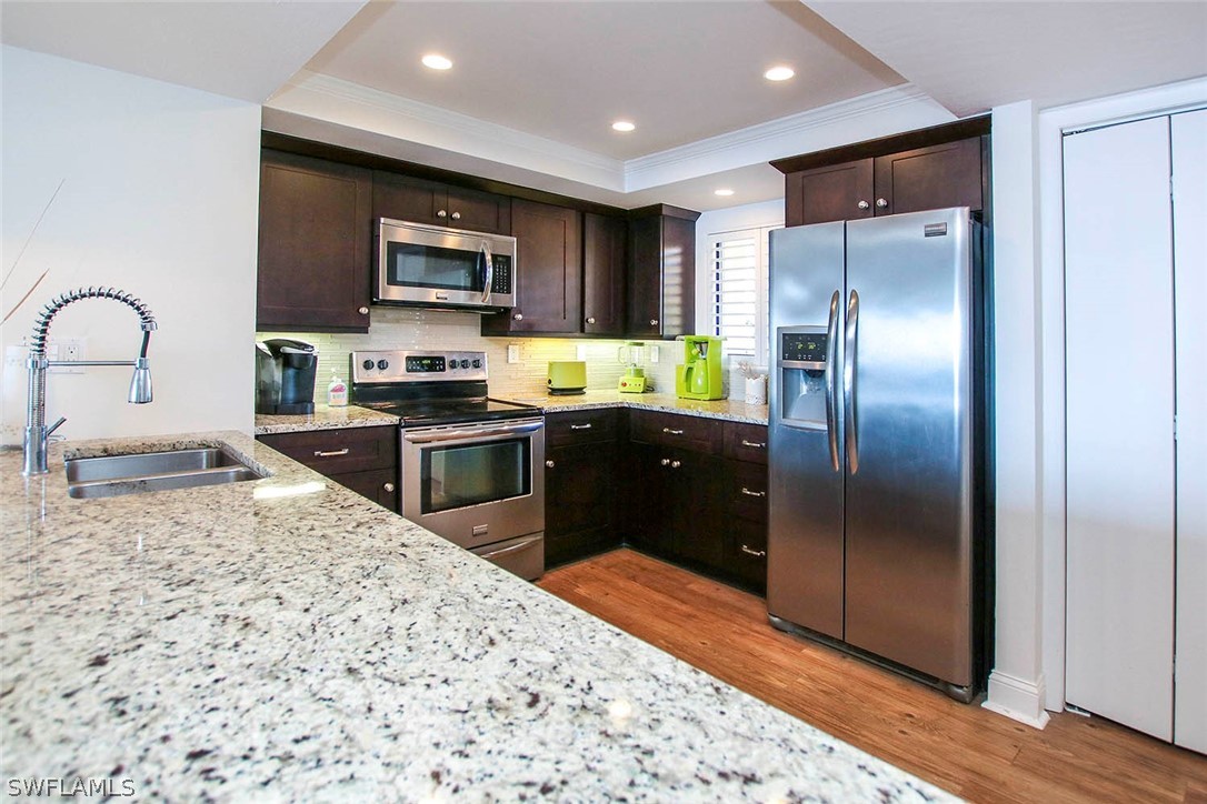 15011 Punta Rassa Road, Unit 204 Fort Myers, FL 33908 - Photo 10 of 23 a kitchen with stainless steel appliances granite countertop a refrigerator a stove a sink and a microwave