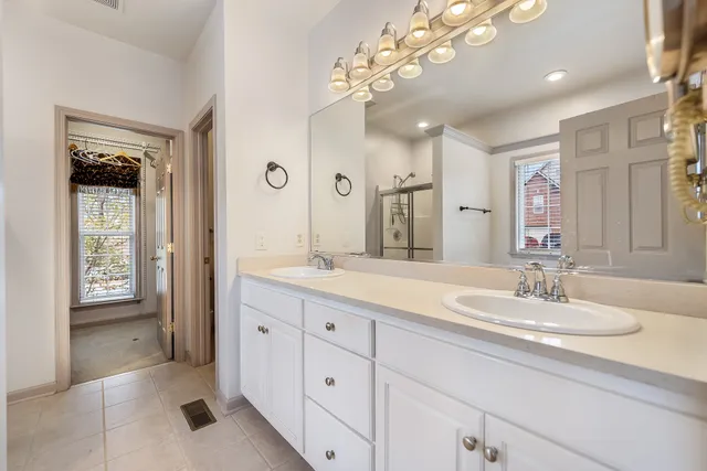 a spacious bathroom with a granite countertop double vanity sink a mirror and window