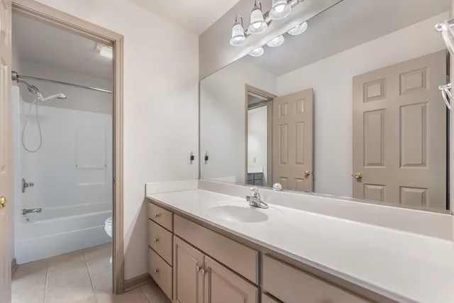 an empty room with chandelier fan and windows