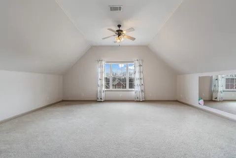 an empty room with chandelier fan and windows