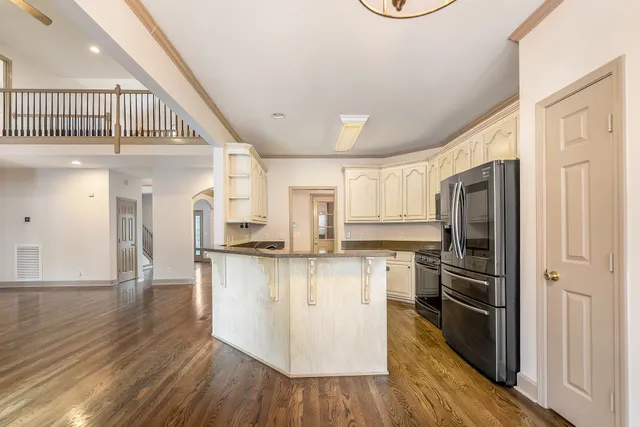 a kitchen with stainless steel appliances granite countertop a refrigerator a stove and a wooden floors