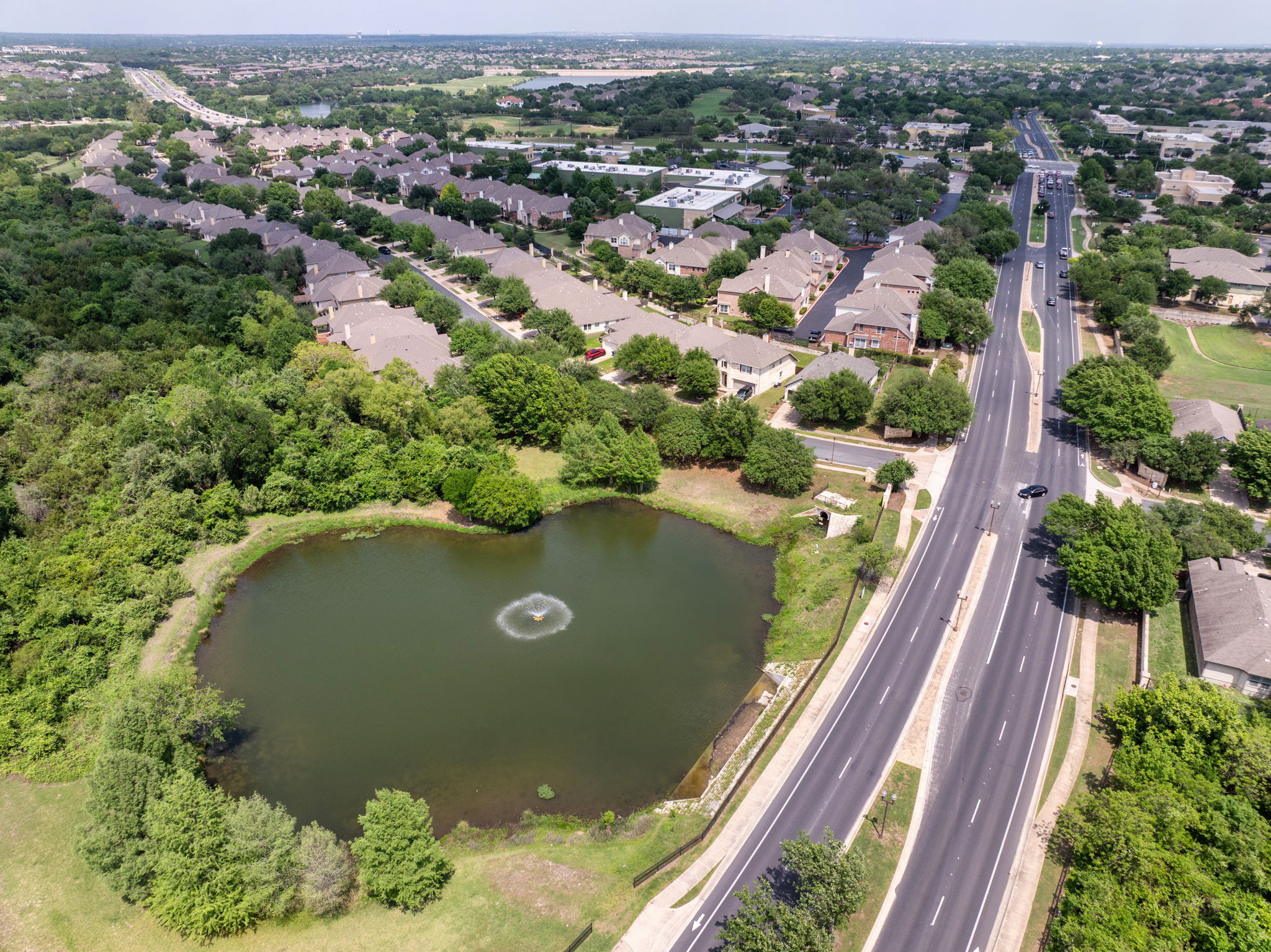 14815 Avery Ranch Boulevard, Unit 1401 Austin, TX 78717 - Photo 28 of 38 Aerial view showcasing a residential community with mature trees and a tranquil pond featuring a fountain