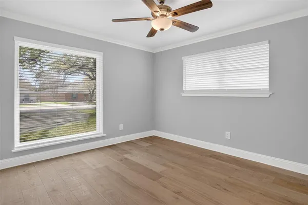 a view of an empty room with a window and wooden floor