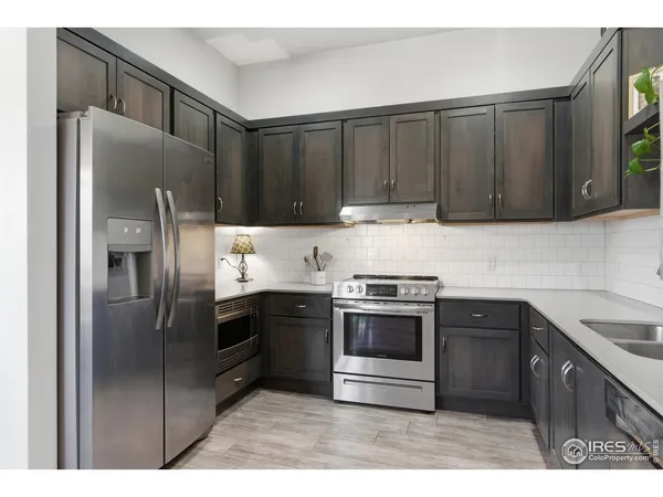 a kitchen with stainless steel appliances granite countertop a stove a refrigerator and a sink