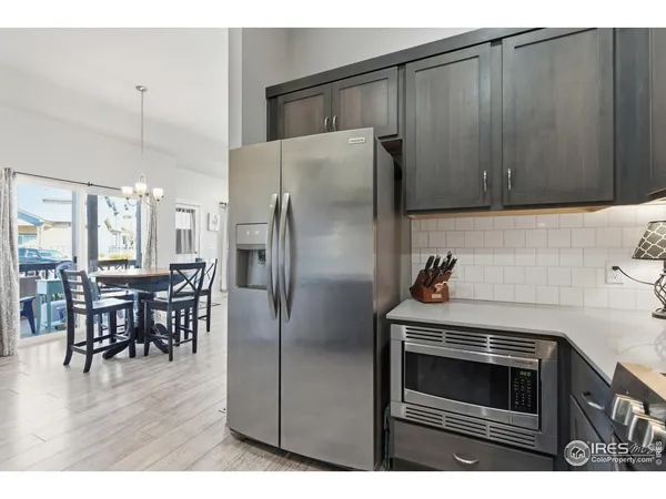 a kitchen with stainless steel appliances a refrigerator a stove a dining table and chairs with wooden floor