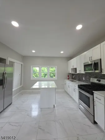 a view of kitchen with stainless steel appliances granite countertop a stove and a sink