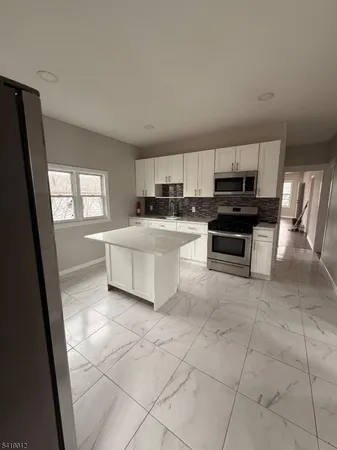 a large white kitchen with a stove a sink a microwave and a window