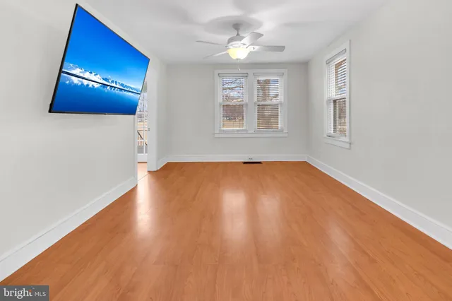 a view of an empty room with a window and wooden floor