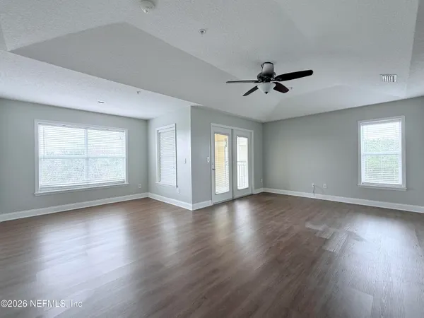 a view of an empty room with wooden floor and a window