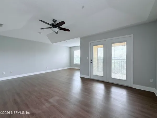 an empty room with wooden floor fan and windows