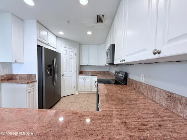 a kitchen with stainless steel appliances granite countertop a refrigerator and a stove top oven