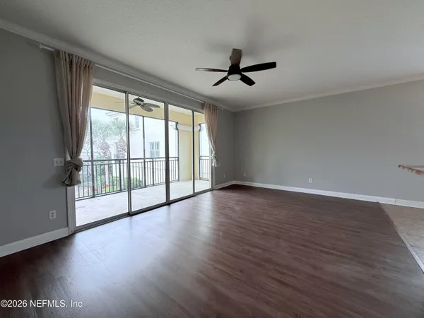 a view of empty room with wooden floor and fan