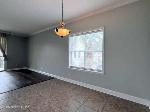 a view of an empty room with a window and chandelier fan