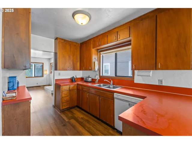 a kitchen with stainless steel appliances granite countertop a sink dishwasher stove and cabinets with wooden floor
