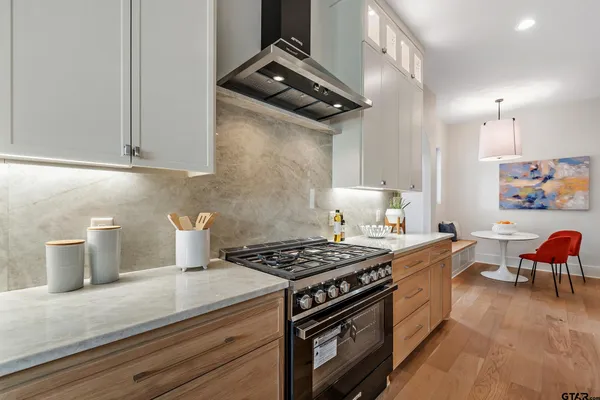 a kitchen with stainless steel appliances granite countertop a sink a stove and white cabinets with wooden floor