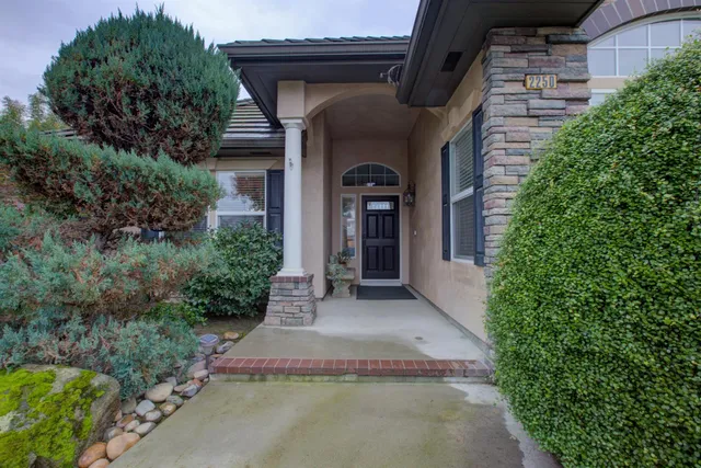 a view of a house with potted plants next to a yard
