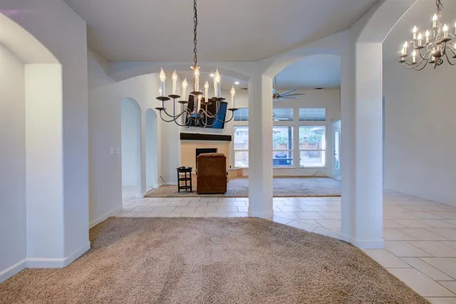 a view of a livingroom with a fireplace a chandelier and windows