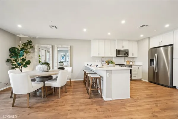 a kitchen with stainless steel appliances kitchen island granite countertop a table chairs sink refrigerator and microwave