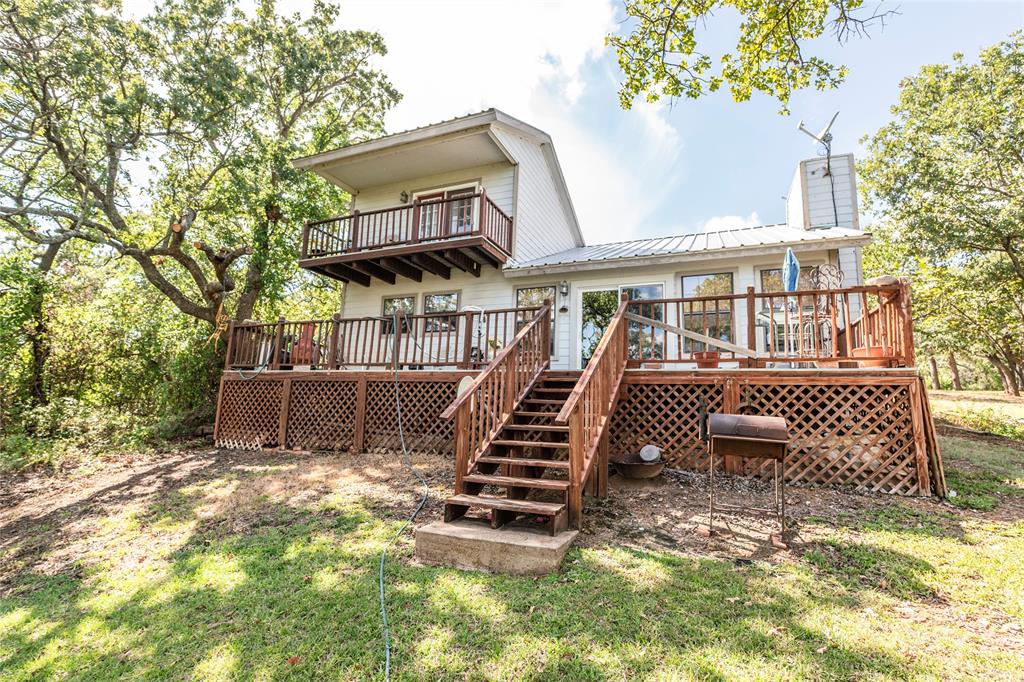 698 Storey Road Nocona, TX 76255 - Photo 5 of 34 Rear view of house featuring a deck, a chimney, a metal roof, stairway, and a balcony