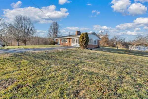 a view of a big house with a big yard and large trees