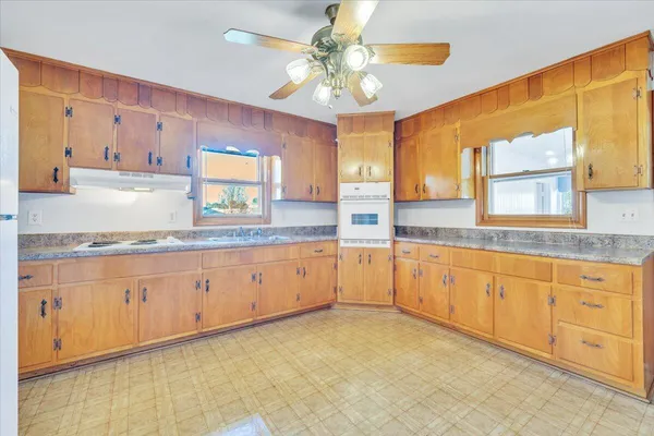 a large kitchen with granite countertop a sink stainless steel appliances white cabinets and a window