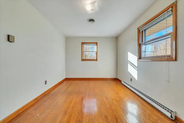a view of an empty room with window and wooden floor
