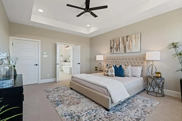 a bedroom with a large bed and a chandelier fan