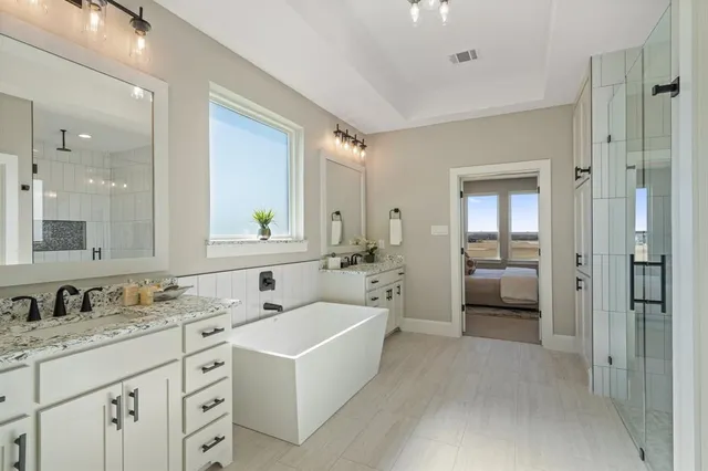 a bathroom with a granite countertop sink double mirror and a shower
