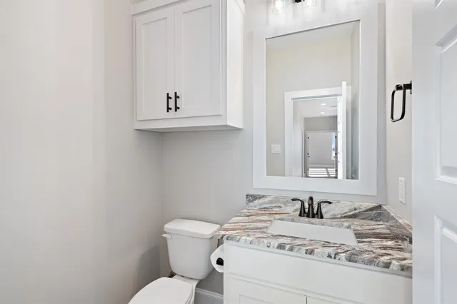 a bathroom with a granite countertop toilet sink and mirror
