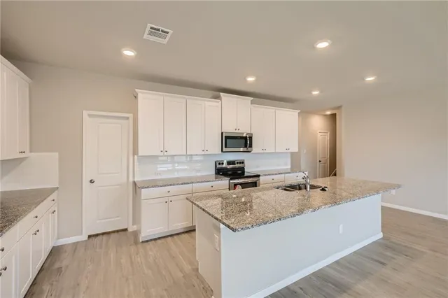 a kitchen with stainless steel appliances granite countertop a sink stove and refrigerator