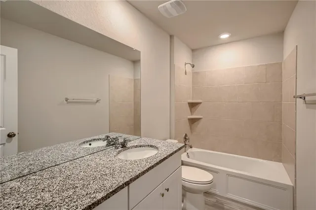 a bathroom with a granite countertop sink a toilet and shower