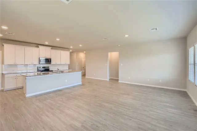 a large kitchen with stainless steel appliances kitchen island a large counter top and a stove top oven