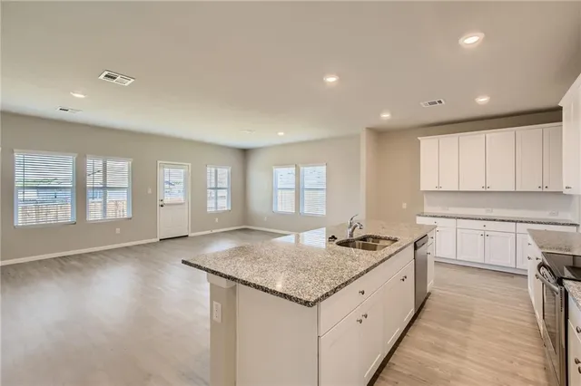 a kitchen with granite countertop kitchen island a sink appliances and a counter space