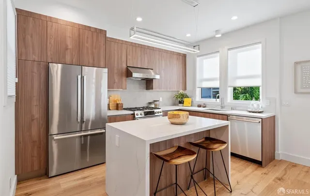 a kitchen with stainless steel appliances a stove a refrigerator and a sink