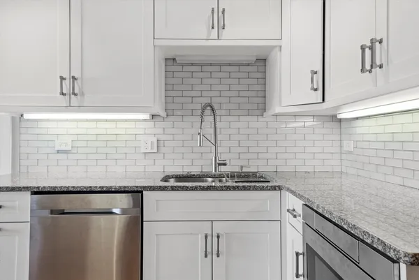 a kitchen with granite countertop white cabinets and white appliances