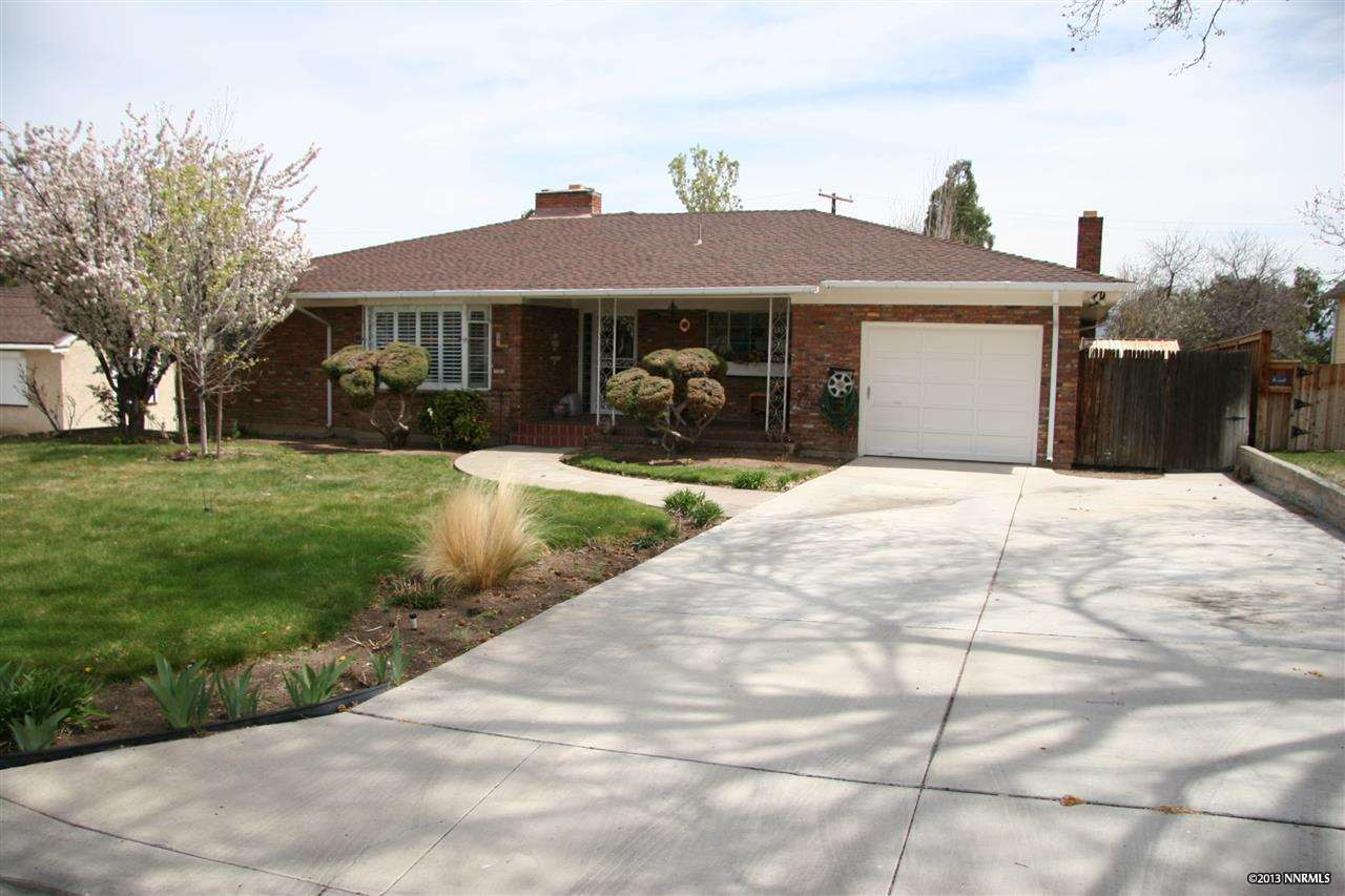 a front view of house with yard and trees in the background