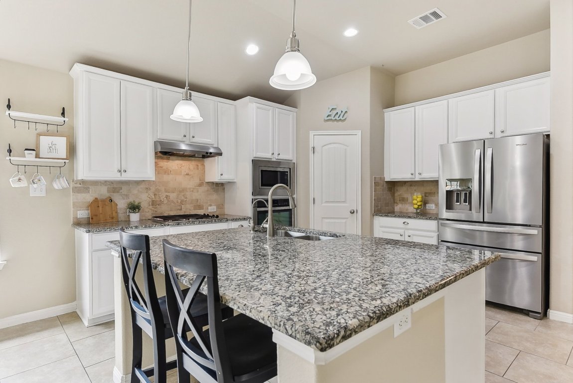 a kitchen with kitchen island granite countertop a sink a center island stainless steel appliances and cabinets