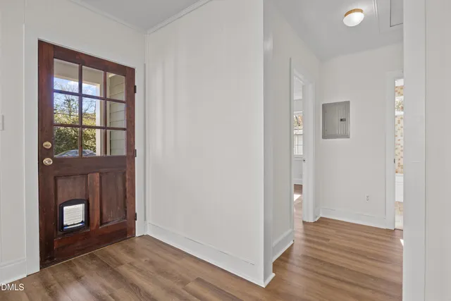 a view of an empty room with wooden floor and a window