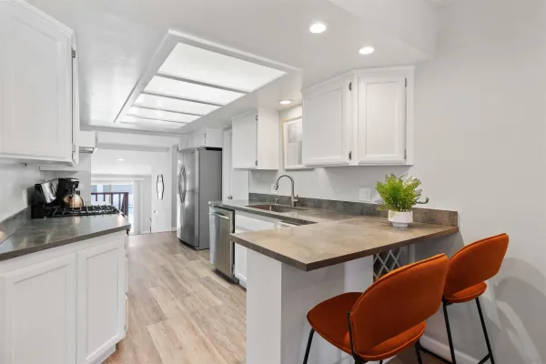 a kitchen with stainless steel appliances granite countertop a table chairs sink and cabinets