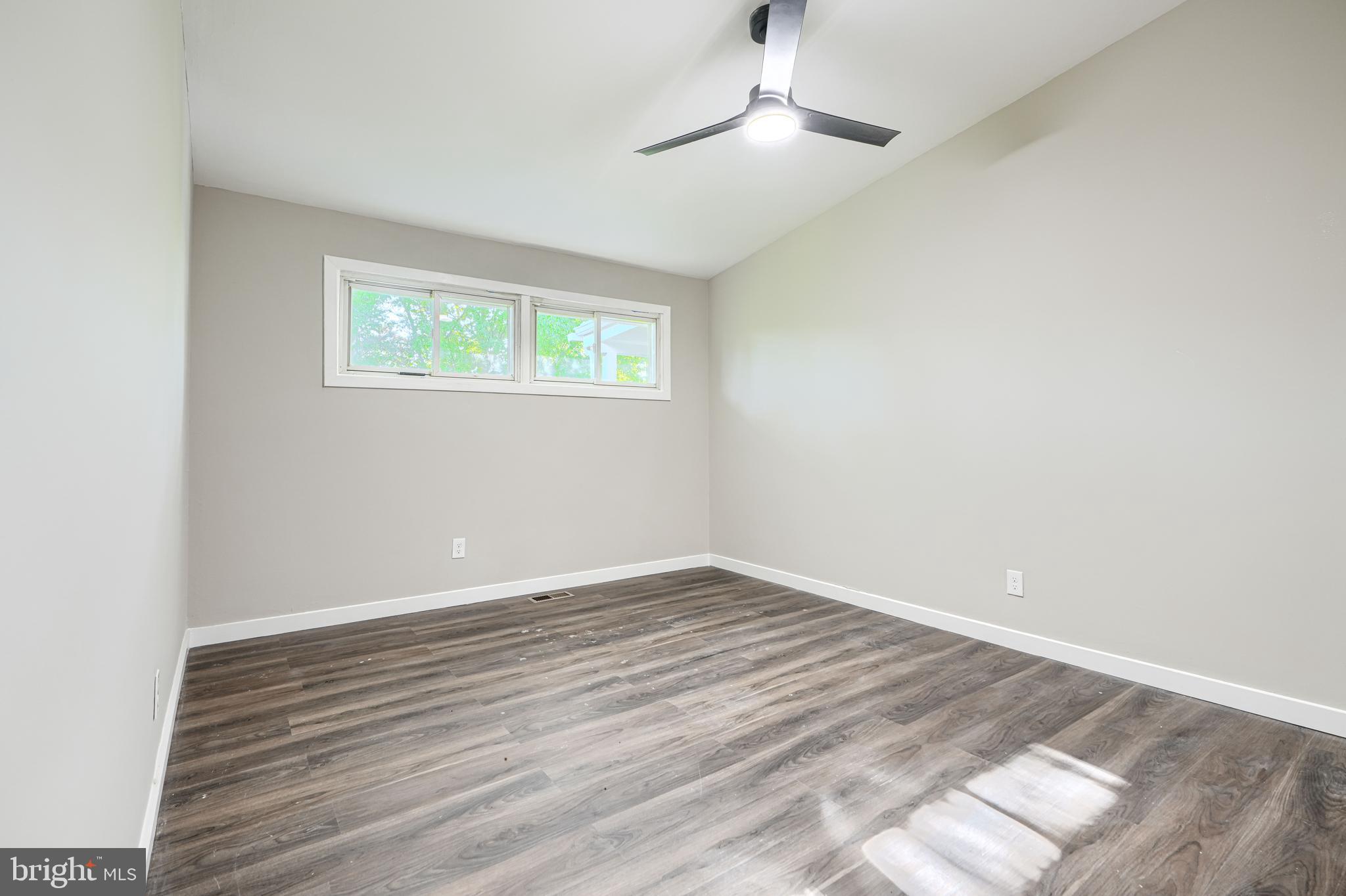 6200 Ivymount Road Baltimore, MD 21209 - Photo 25 of 71 an empty room with wooden floor chandelier fan and windows